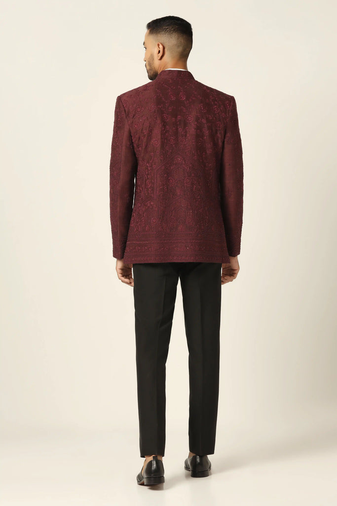 Drape in sophistication with our raw silk Bandhgala suit. The maroon coat boasts intricate tonal embroidery, paired flawlessly with jet black trousers.