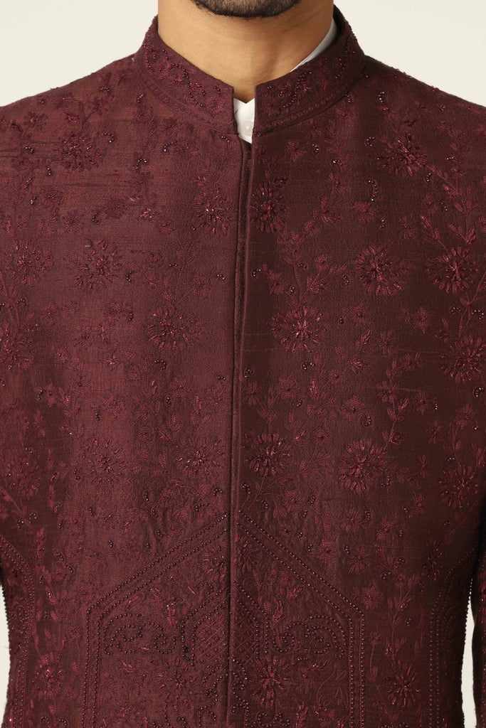 Drape in sophistication with our raw silk Bandhgala suit. The maroon coat boasts intricate tonal embroidery, paired flawlessly with jet black trousers.