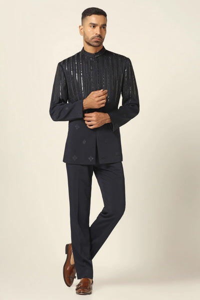 Elevate your style with our Navy bandhgala, crafted in all-weather suiting fabric. Featuring contemporary design with thread embroidery and metal tape, paired with black trousers.