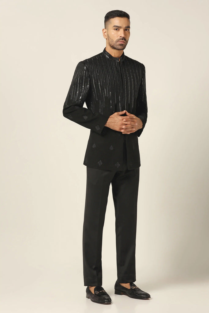Dress in sophistication with our black bandhgala, crafted in all-weather suiting fabric. Featuring contemporary design with thread embroidery and metal tape, paired with black trousers.