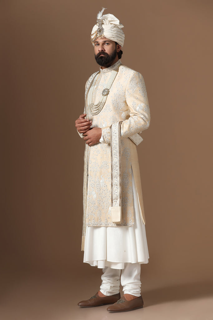 Elevate your style with our beige sherwani, featuring intricate floral and bird embroidery. Paired with a long kurta and pajama set. Accessories sold separately.