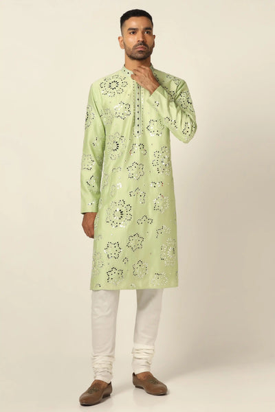 This Kurta Pajama set is crafted from luxurious Chanderi silk fabric. The green Kurta features exquisite mirror embroidery and threadwork, paired with off-white churidar pajamas for a sophisticated look.