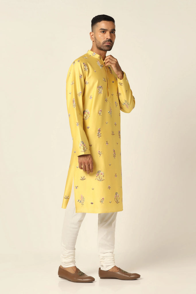 Crafted in luxurious chanderi fabric, this Kurta Pajama set features vibrant floral motifs adorning the yellow kurta. Paired with off-white churidar pajamas for a complete look.