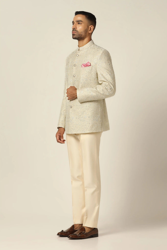 Drape in elegance with our raw silk Bandhgala suit. The coat features intricate hand embroidery, blending Thread and Zari work, paired with matching off-white trousers.