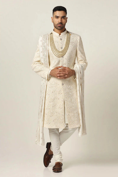 Step into sophistication with our elegant Sherwani set, crafted from premium Raw silk. Adorned with intricate machine embroidery, it comes complete with a classic Kurta pajama ensemble.
