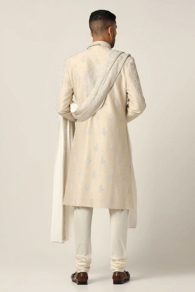 Draped in opulent Raw silk, this Sherwani set boasts pearl hand and machine embroidery, exuding timeless elegance. Complete with Kurta Pajama ensemble for sophistication.