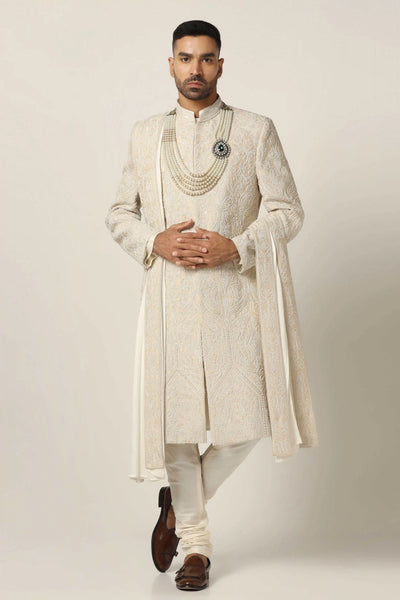 Draped in opulent Raw silk, this Sherwani set boasts pearl hand and machine embroidery, exuding timeless elegance. Complete with Kurta Pajama ensemble for sophistication.