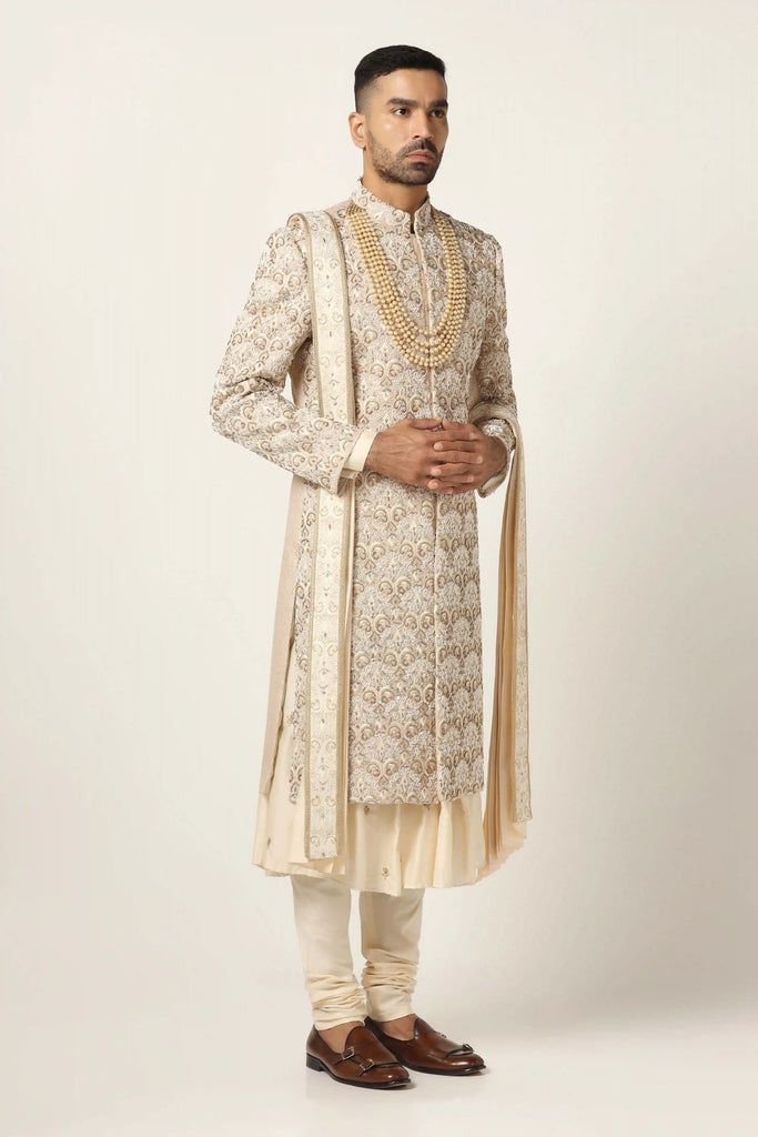 Elevate your style with our beige Sherwani, adorned with floral and geometric embroidery. Complete with a pleated Kurta and Pajama set for timeless elegance.