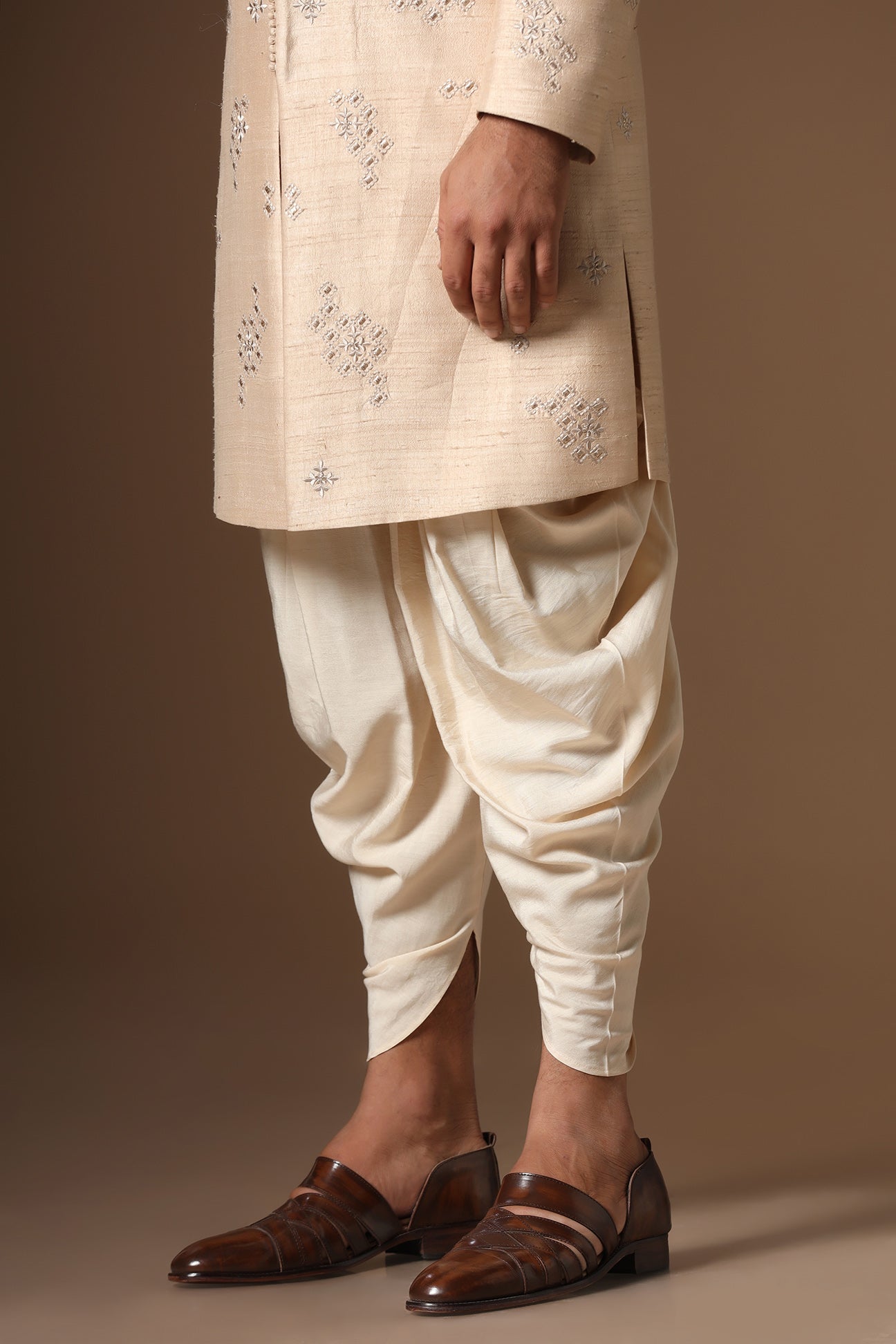 This beige Indo-Western made with raw silk fabric is highlighted by intricate embroidery. Shop Now!