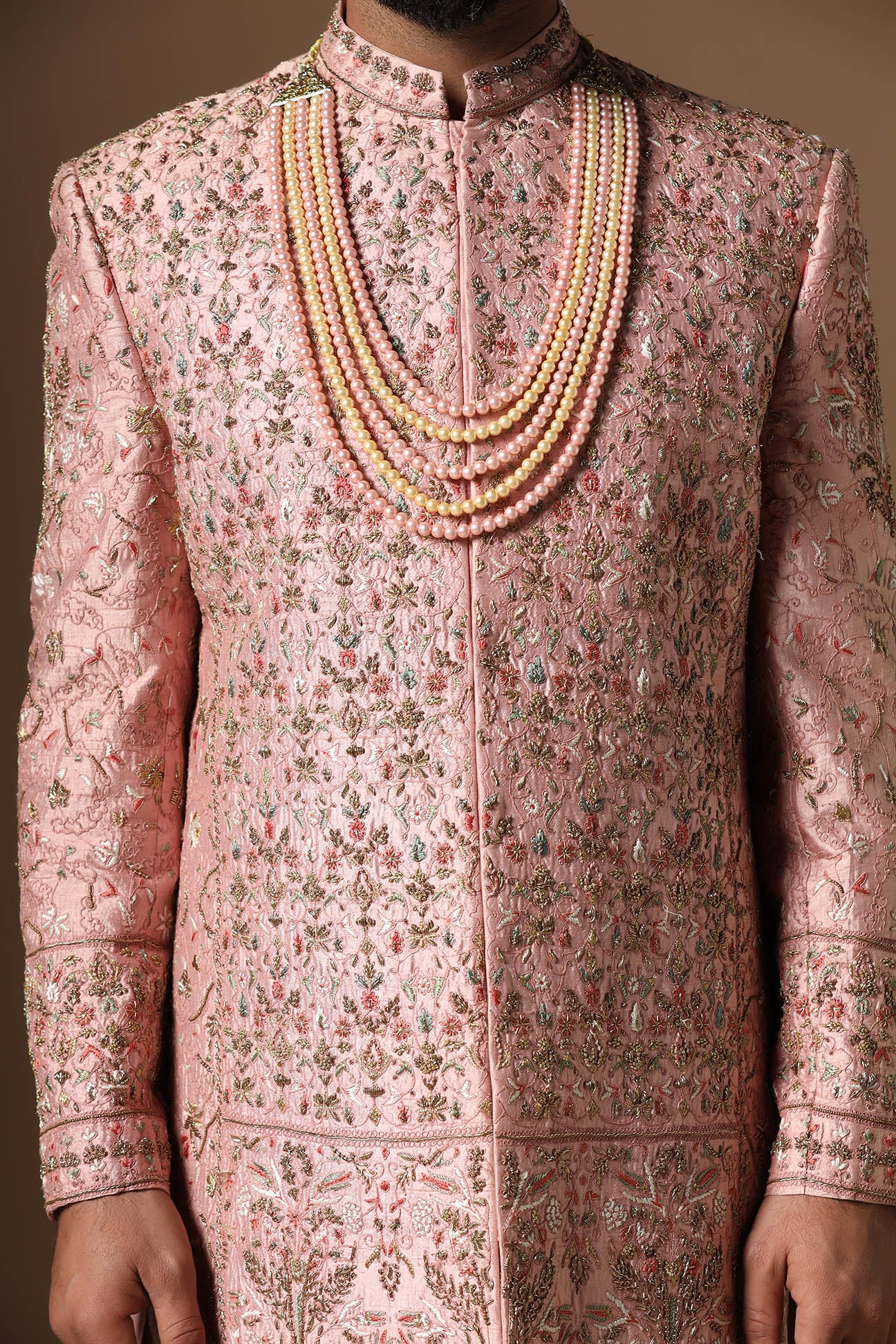 This peach Sherwani is highlighted by intricate floral embroidery across the garment. Shop Now!