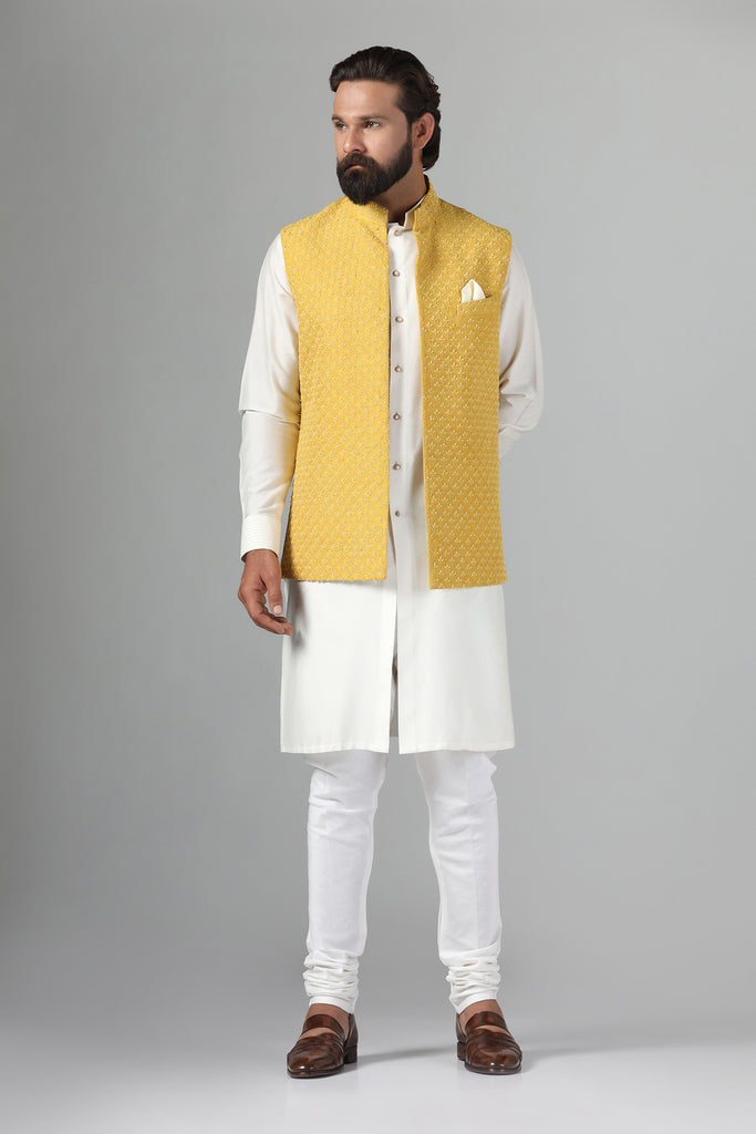 Elevate your style with our Yellow Nehru Jacket, adorned with tonal embroidery for timeless elegance. Paired with an off-white front open kurta and churidar trousers.