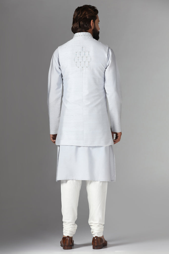 Elevate your style with our long grey raw silk Nehru Jacket, adorned with geometric embroidery. Paired seamlessly with a monochrome kurta pajama ensemble.