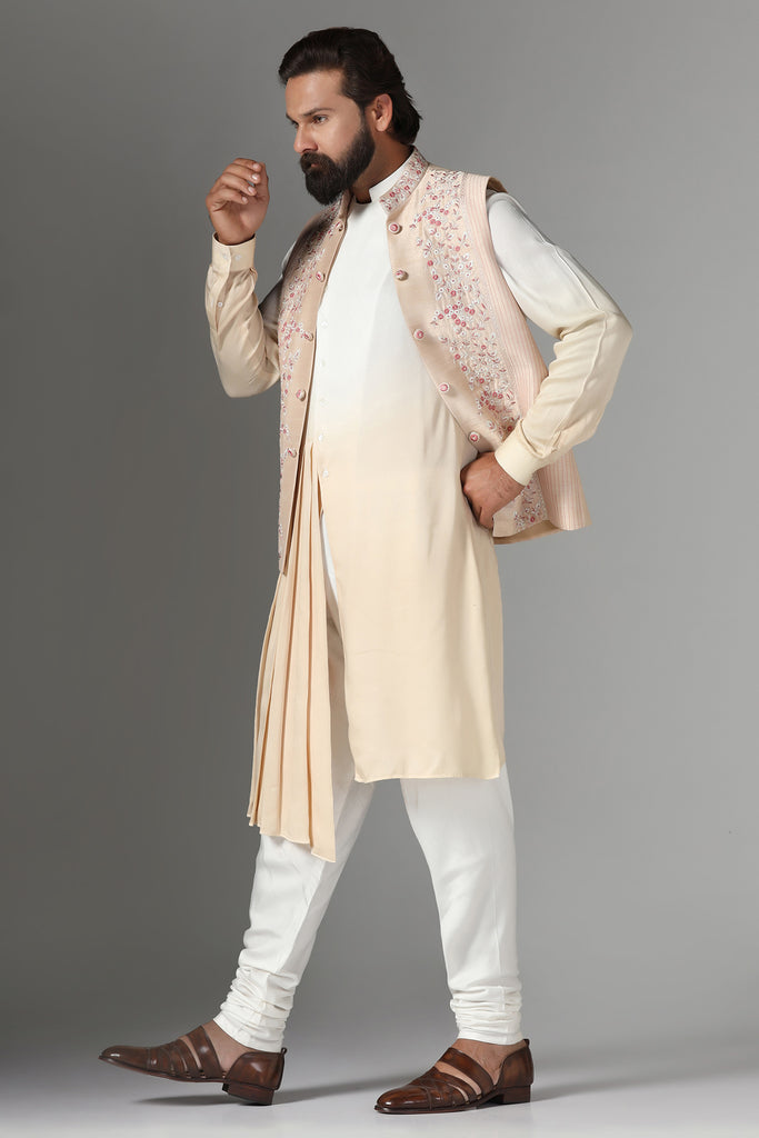 Elevate your style with our light peach raw silk Nehru Jacket adorned with floral embroidery and pintucks. Paired with an ombre pleated kurta and pajama for a stunning ensemble.