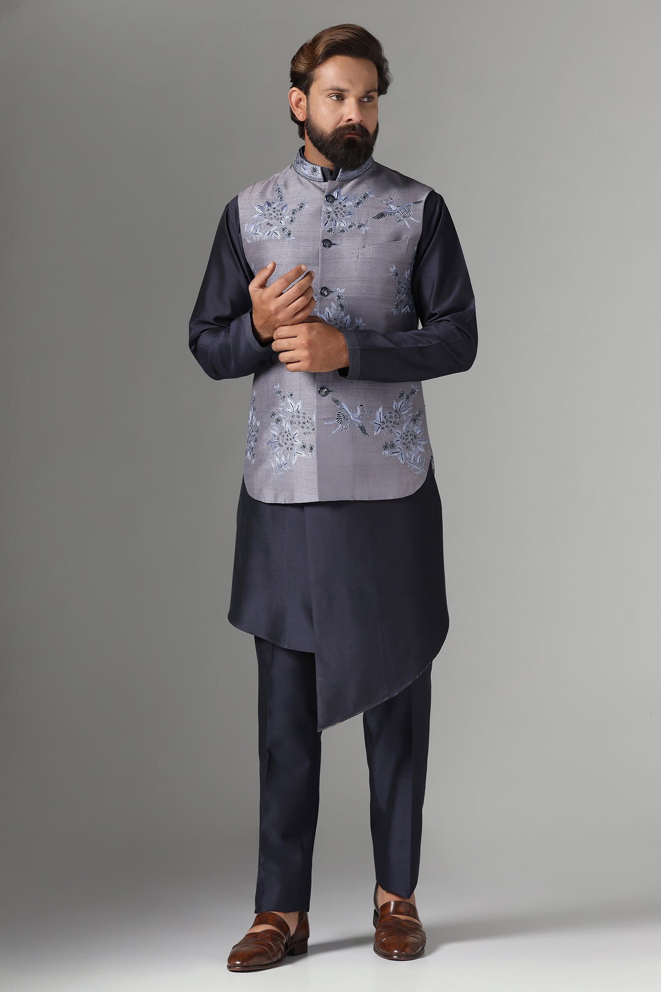 Enhance your style with our grey raw silk Nehru jacket adorned with floral embroidery. Shop Now!