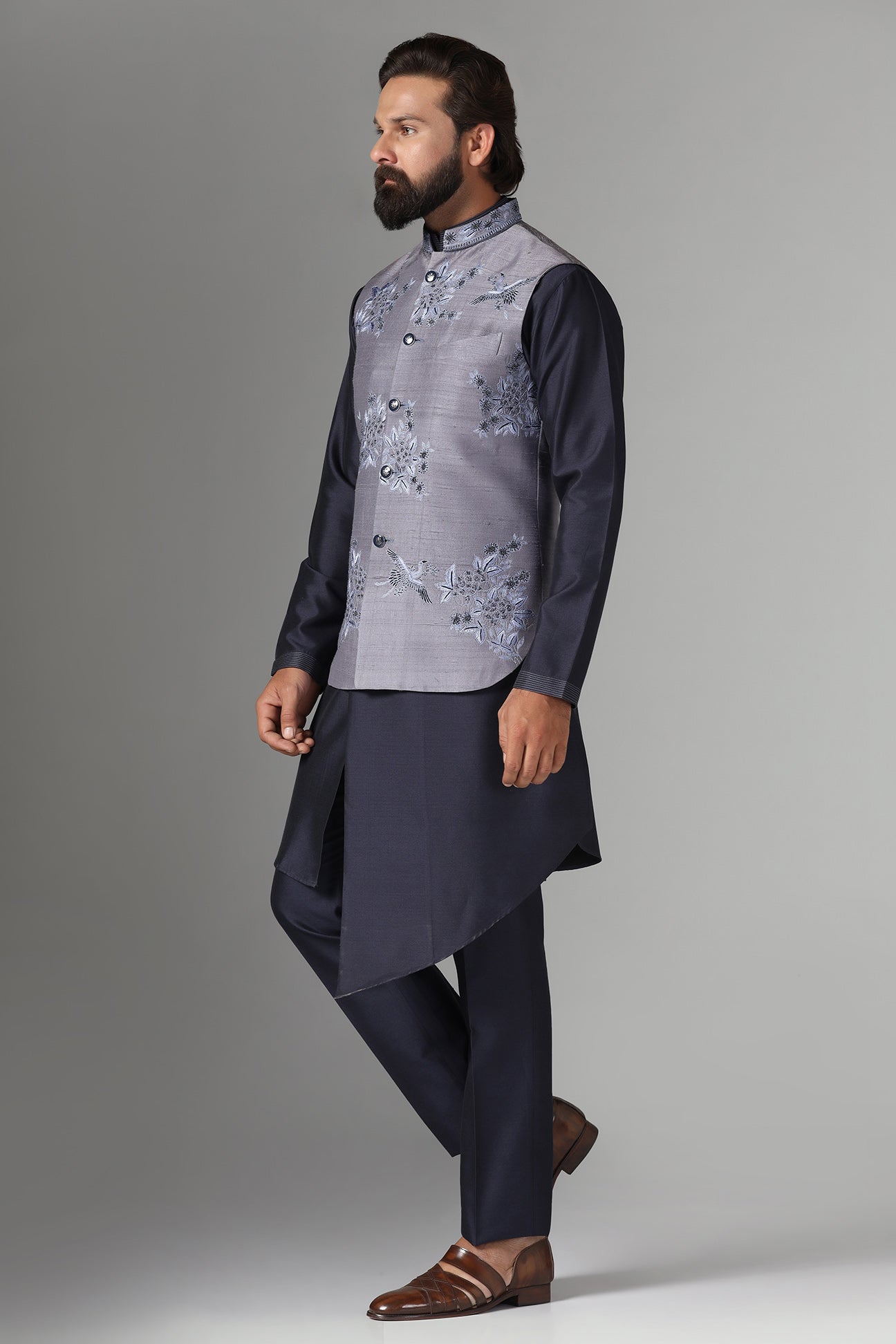 Enhance your style with our grey raw silk Nehru jacket adorned with floral embroidery. Shop Now!