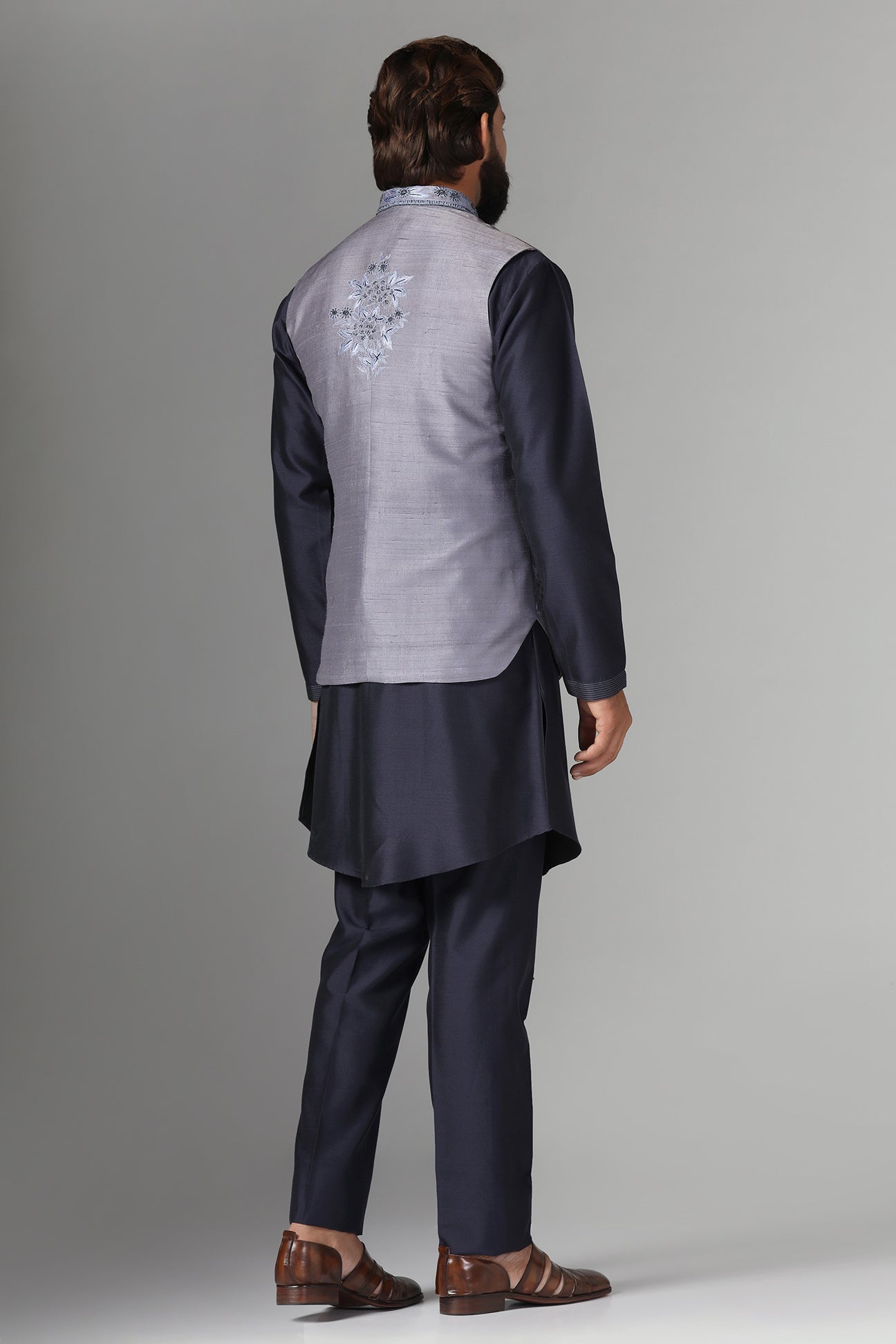 Enhance your style with our grey raw silk Nehru jacket adorned with floral embroidery. Shop Now!