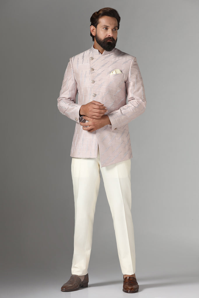 Dress with grace in our soft pink asymmetric Bandhgala suit, tailored from raw-silk fabric. Adorned with diagonal line motif embroidery, paired with off-white trousers for a refined look.