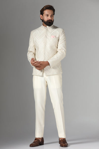 Elevate your style with our off-white Bandhgala suit in raw-silk fabric, featuring zig-zag embroidery. Trousers boast a tapered, flat-front design for a refined look.