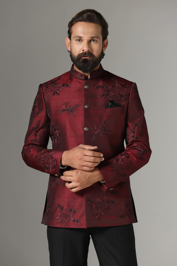 Dress with elegance in our maroon Bandhgala suit, crafted from raw-silk fabric. Embroidered with birds and floral motifs, paired with jet-black trousers for a refined ensemble.