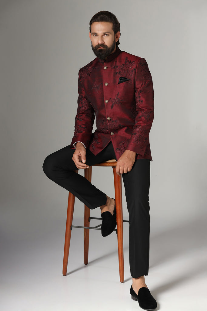 Dress with elegance in our maroon Bandhgala suit, crafted from raw-silk fabric. Embroidered with birds and floral motifs, paired with jet-black trousers for a refined ensemble.