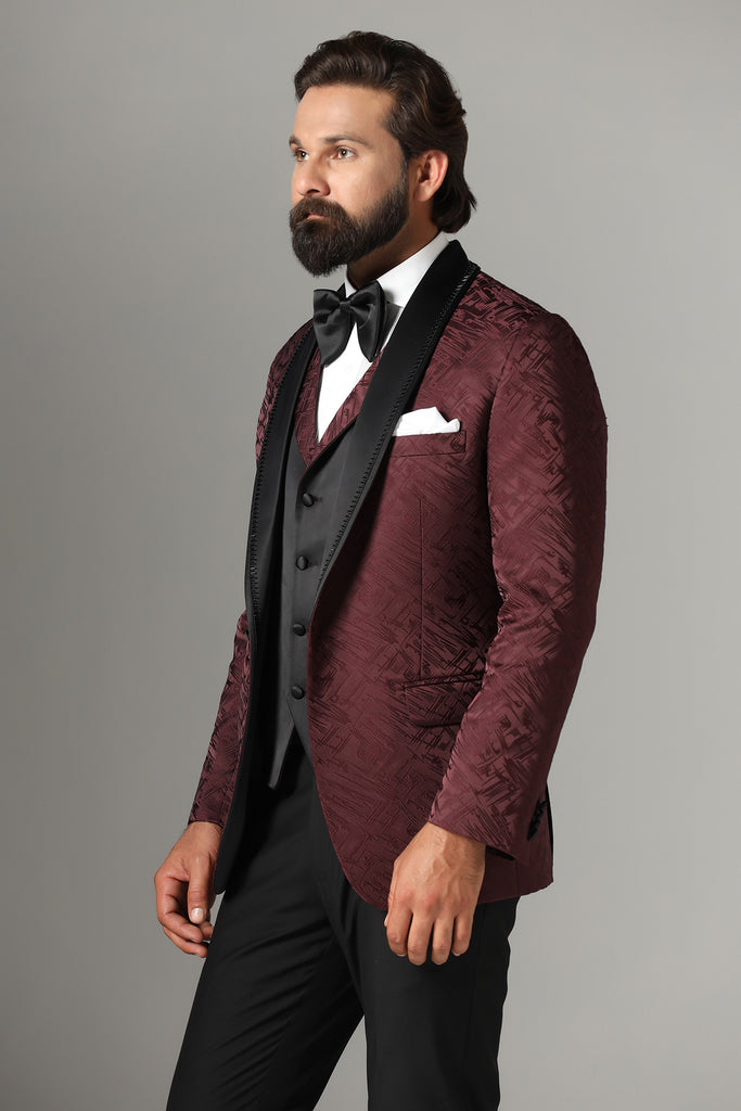 Elevate your style with our Textured Maroon Tuxedo. Satin shawl collar with subtle embroidery, paired with a matching waistcoat. Jet-Black trousers complete the ensemble.
