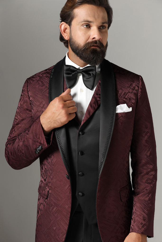 Elevate your style with our Textured Maroon Tuxedo. Satin shawl collar with subtle embroidery, paired with a matching waistcoat. Jet-Black trousers complete the ensemble.