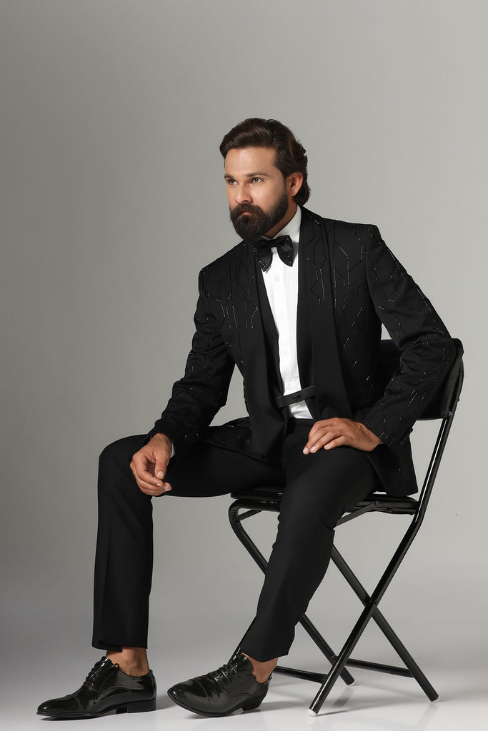 Elevate your style with our Black Three-Piece Tuxedo. Intricate embroidery throughout, modern cut shawl lapel. Accessories sold separately.