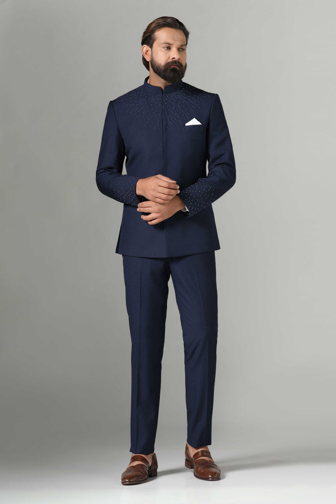 Dress with sophistication in our Navy Blue Bandhgala suit, tailored from wool-rich fabric. Delicate embroidery on the neck and sleeves adds elegance. Paired with navy blue trousers.