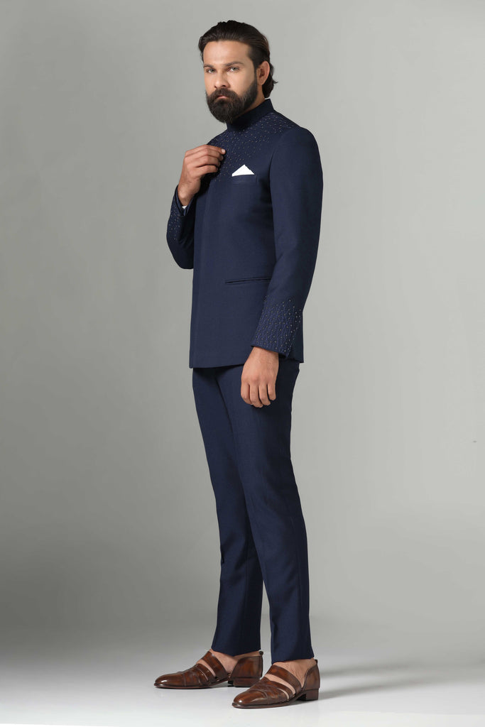 Dress with sophistication in our Navy Blue Bandhgala suit, tailored from wool-rich fabric. Delicate embroidery on the neck and sleeves adds elegance. Paired with navy blue trousers.