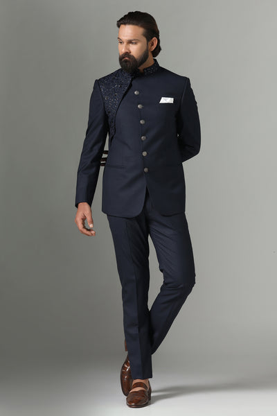 Exude elegance in our midnight blue asymmetric Bandhgala suit, tailored from wool-rich fabric. Highlighted by an embroidered asymmetric panel, paired with tapered, flat-front trousers.