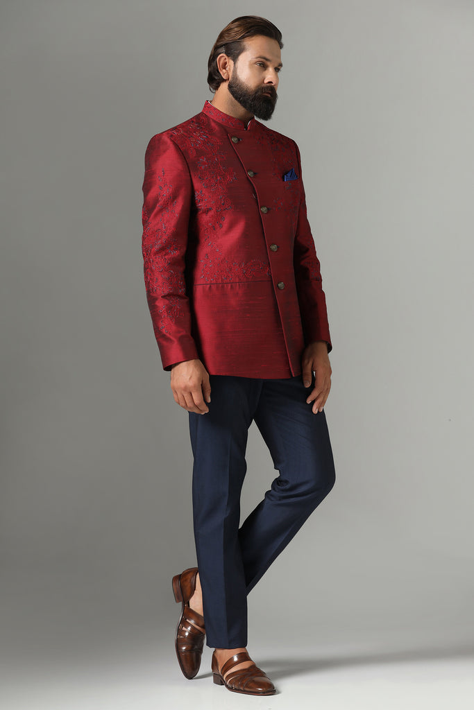 Dress with sophistication in our Red Bandhgala suit, tailored from Raw-Silk fabric and adorned with delicate thread-work embroidery. Paired with navy blue trousers for a refined ensemble.