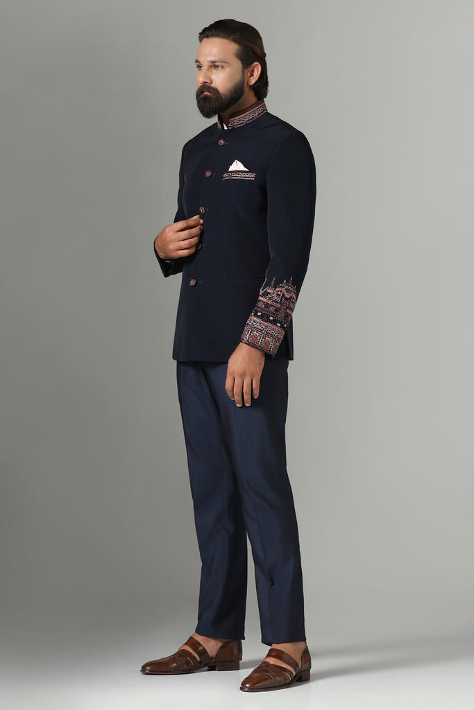 Elevate your style with our Dark Blue Bandhgala suit, featuring contrast embroidery on sleeves, collar, and pocket bone. Paired with navy blue trousers for a refined ensemble.