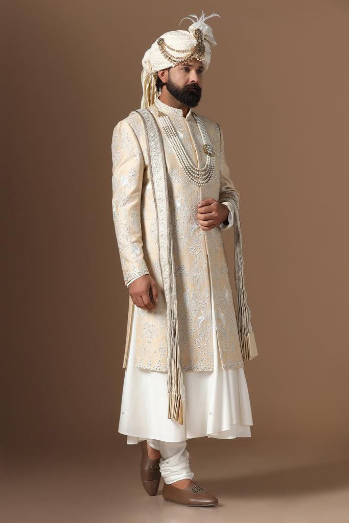 Elevate your style with our beige sherwani, featuring intricate floral and bird embroidery. Paired with a long kurta and pajama set. Accessories sold separately.
