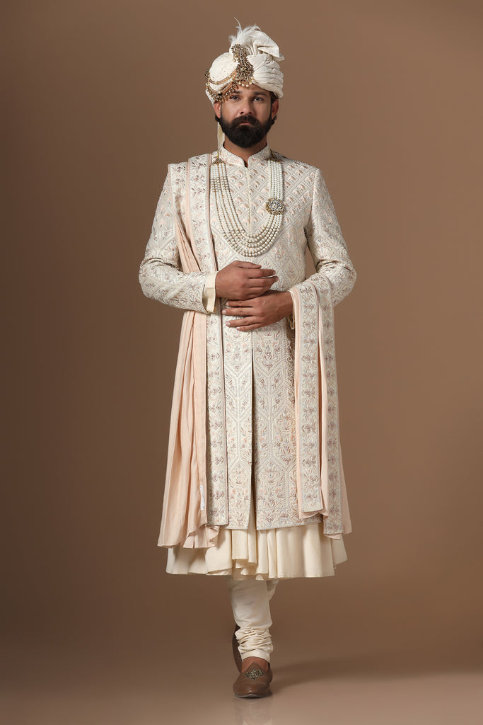 Indulge in elegance with our beige Sherwani, adorned with floral and geometric embroidery. Paired with a pleated kurta and pajama set for a refined look.