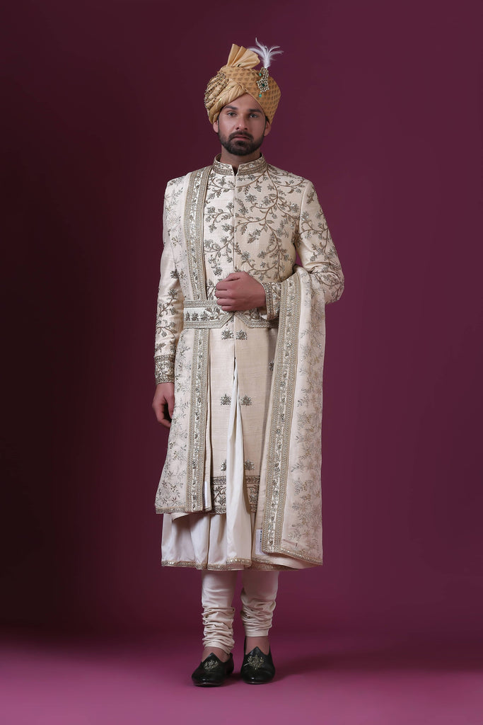 Elevate your style with this classic Sherwani adorned with bold Zari embroidery in a timeless floral pattern. The blend of gold and silver adds exquisite elegance.