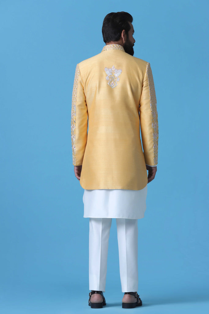 Exude elegance in this soft yellow Raw Silk Indowestern, adorned with intricate off-white dori embroidery. Paired with a matching kurta and silk trousers, it's the epitome of sophistication.