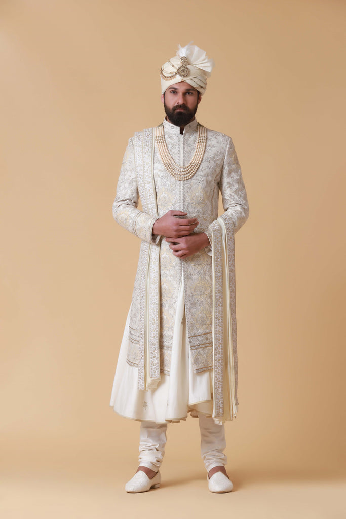 Exude regal elegance in this off-white Sherwani crafted from raw silk, featuring intricate tonal embroidery and patchwork. Paired with a flared kurta and pajama for a complete ensemble.
