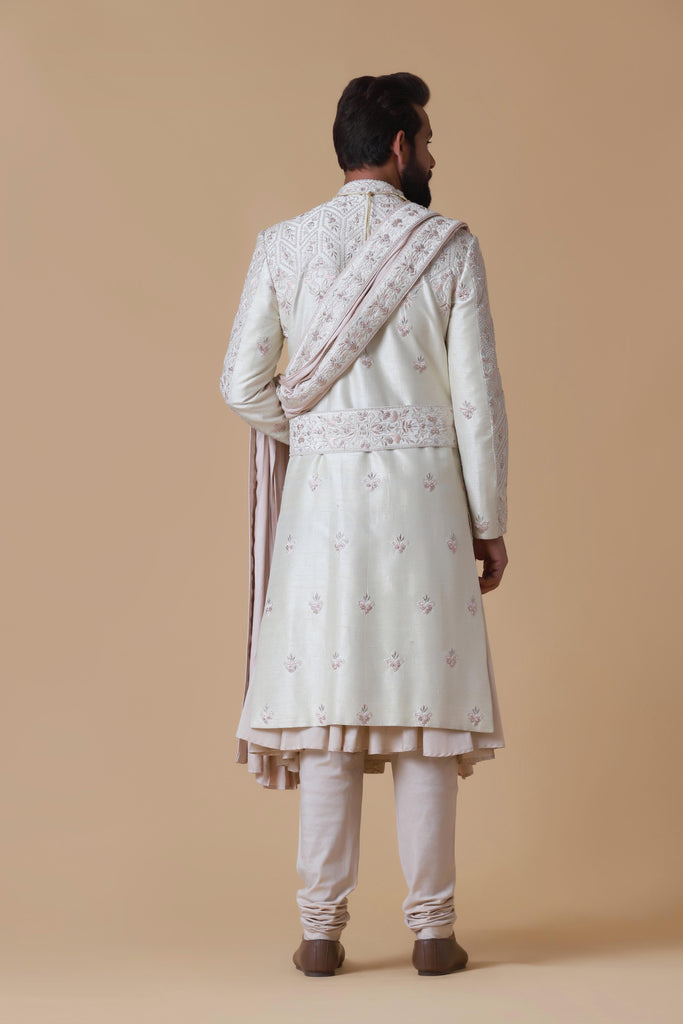Elevate your style with this off-white sherwani, featuring a blend of geometric and floral embroidery. Complete with pleated kurta, pajama, and Kamarband for a refined ensemble.