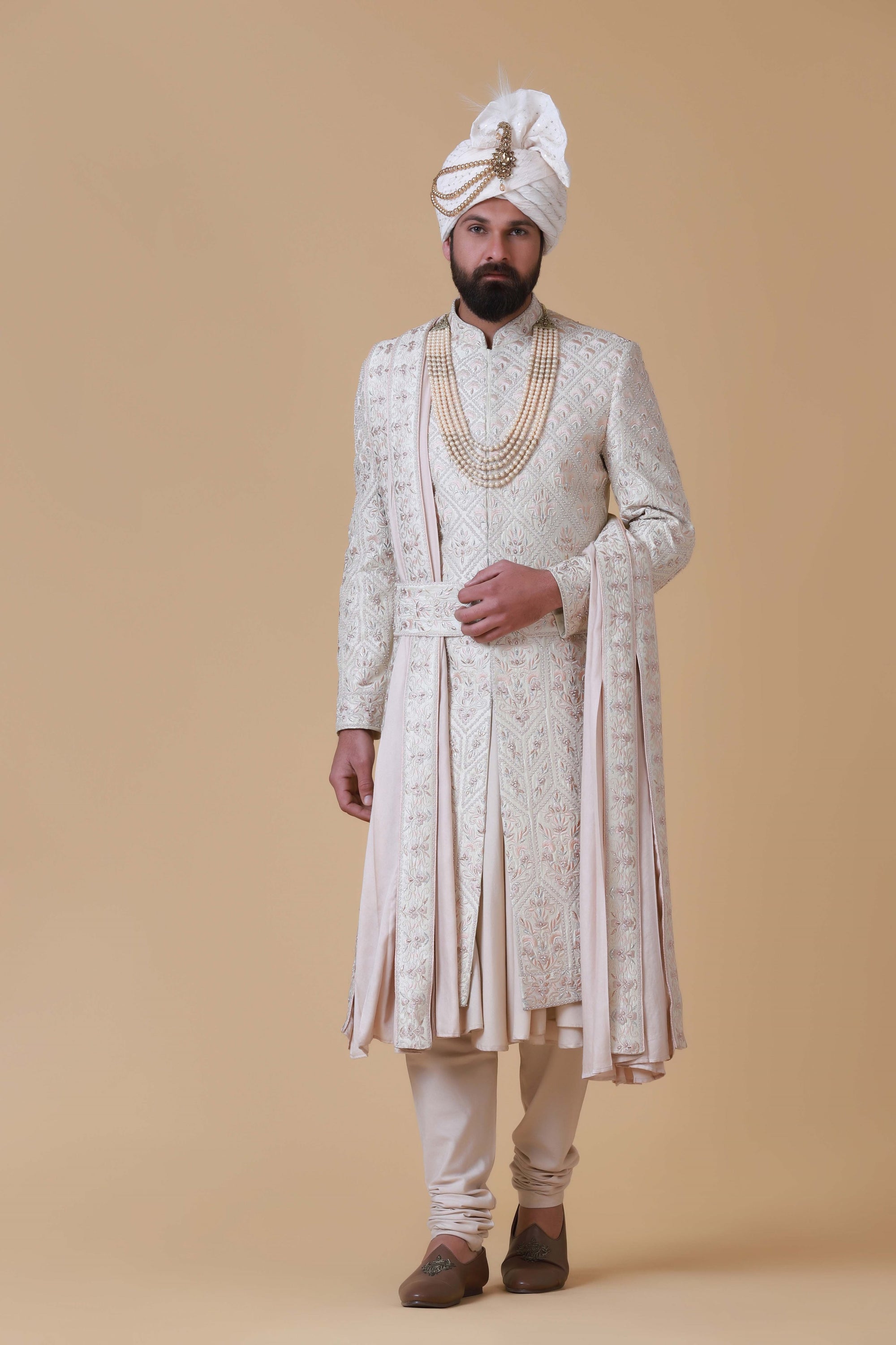 Elevate your style with this off-white sherwani, featuring a blend of geometric and floral embroidery. Complete with pleated kurta, pajama, and Kamarband for a refined ensemble.