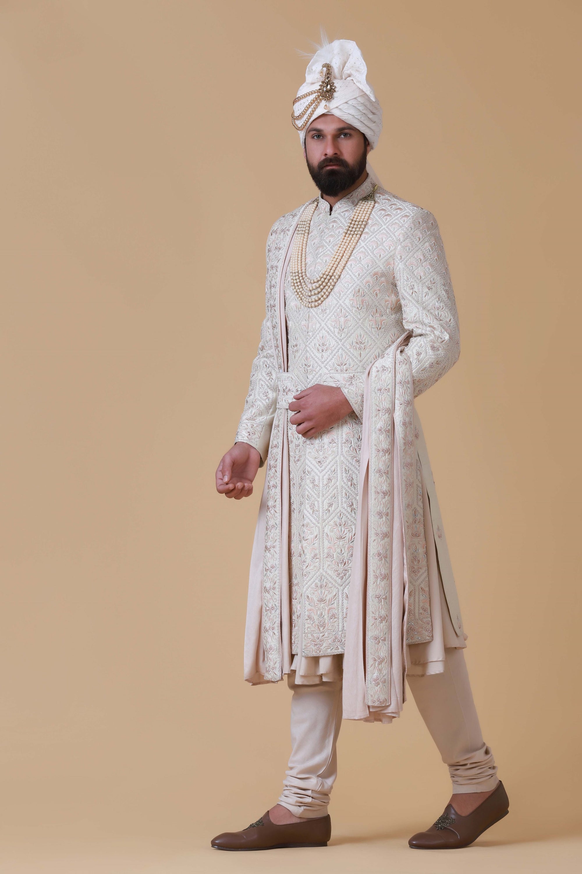 Elevate your style with this off-white sherwani, featuring a blend of geometric and floral embroidery. Complete with pleated kurta, pajama, and Kamarband for a refined ensemble.