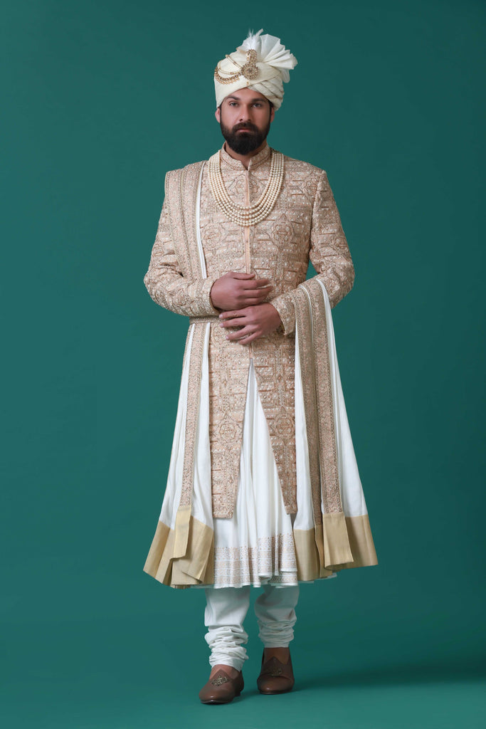Floral and geometric embroidery adorn this beige sherwani, paired with a pleated kurta and pajama set for a harmonious ensemble.