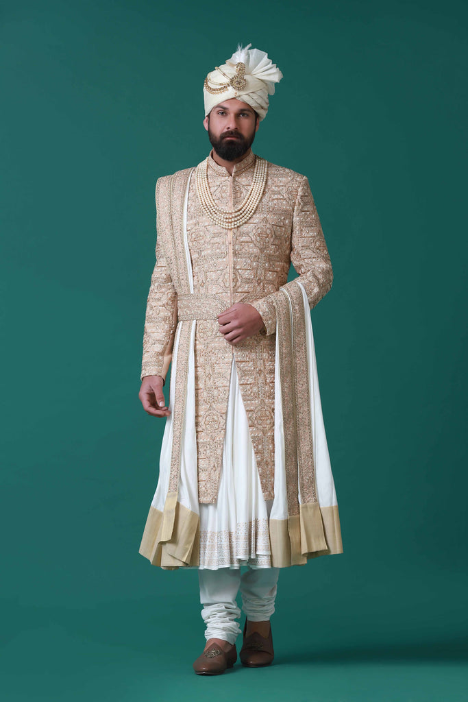 Floral and geometric embroidery adorn this beige sherwani, paired with a pleated kurta and pajama set for a harmonious ensemble.