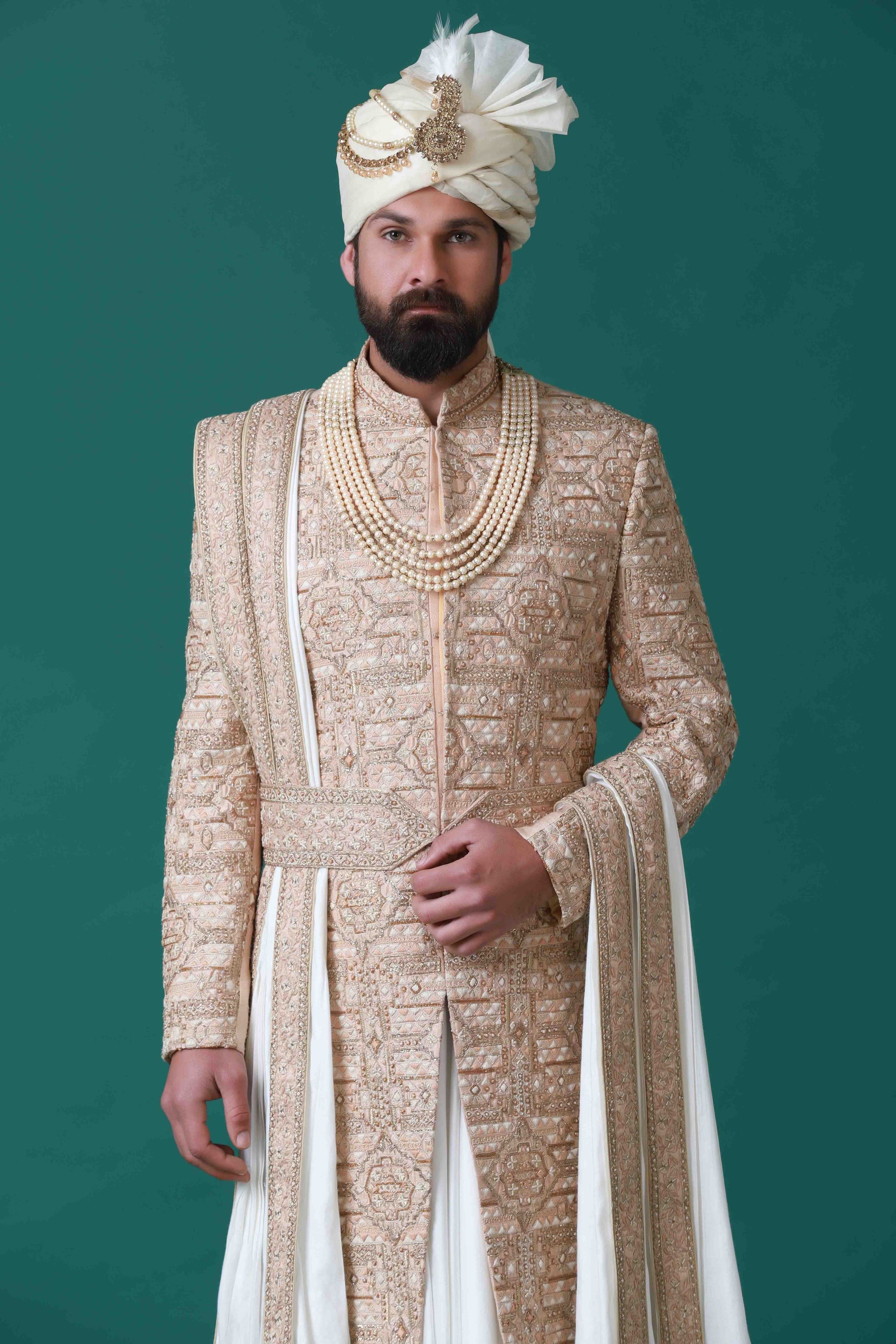 Floral and geometric embroidery adorn this beige sherwani, paired with a pleated kurta and pajama set for a harmonious ensemble.