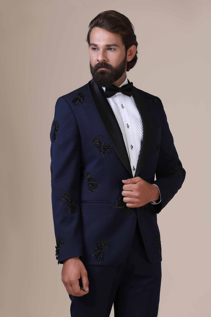 Elevate your style with our shawl collar Tuxedo. Single button closure, navy blue coat adorned with subtle black embroidery. Paired with black trousers.