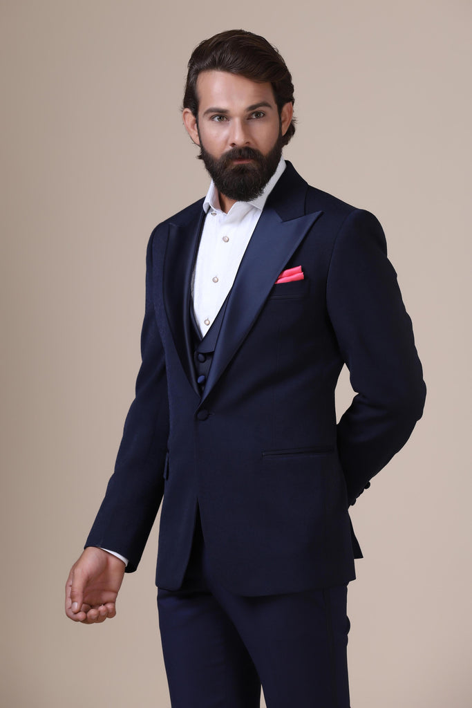 Dress with refined elegance in our Navy tuxedo. Notched lapel, single button closure. Subtle paisley jacquard adds sophistication. Complete with plain Navy waistcoat and trousers.