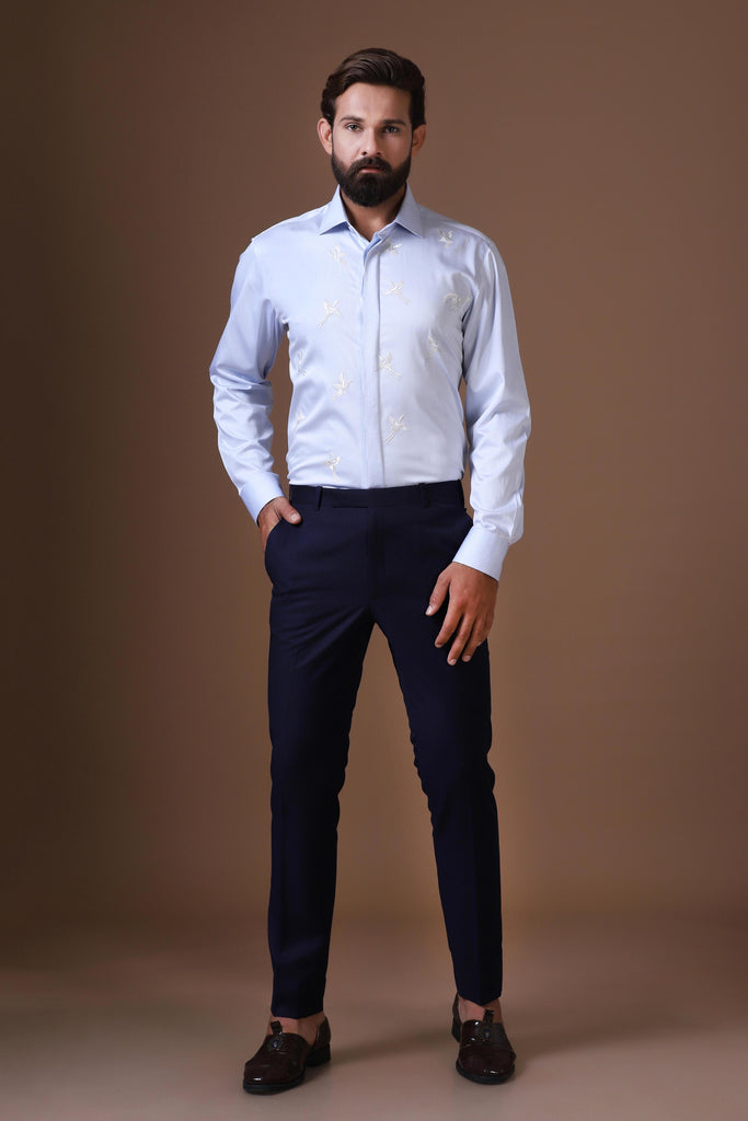 Elevate your look with this sky blue shirt featuring a delicate white bird motif embroidery. Designed with a concealed button placket and spread collar for a refined finish.