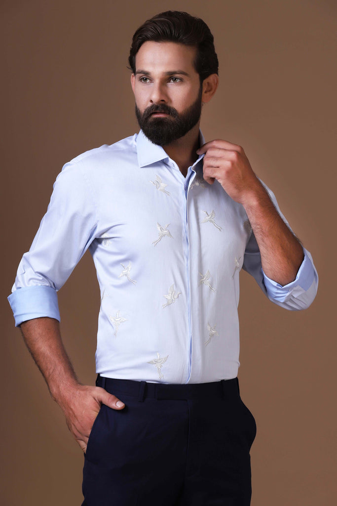 Elevate your look with this sky blue shirt featuring a delicate white bird motif embroidery. Designed with a concealed button placket and spread collar for a refined finish.