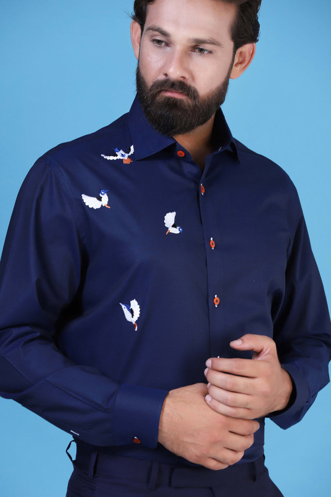 Elevate your style with our navy shirt adorned with embroidered birds on the left. Complete with a regular collar and matching buttons for a polished look.